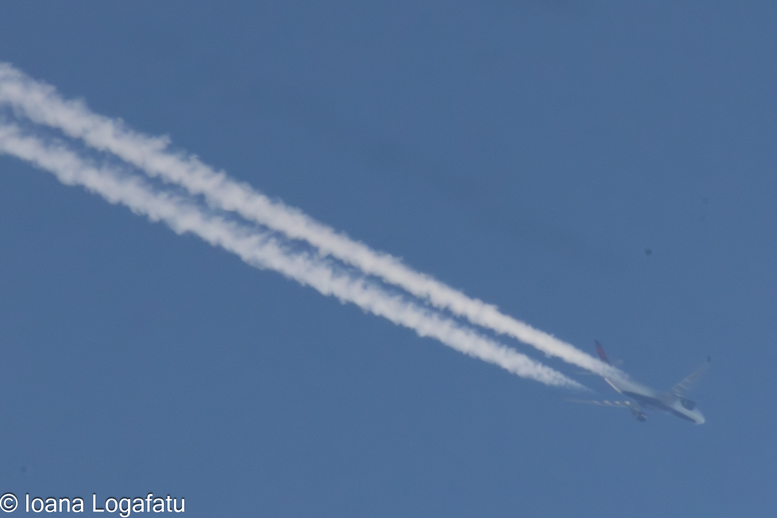 Airplane trails shimmer in the clear blue sky
